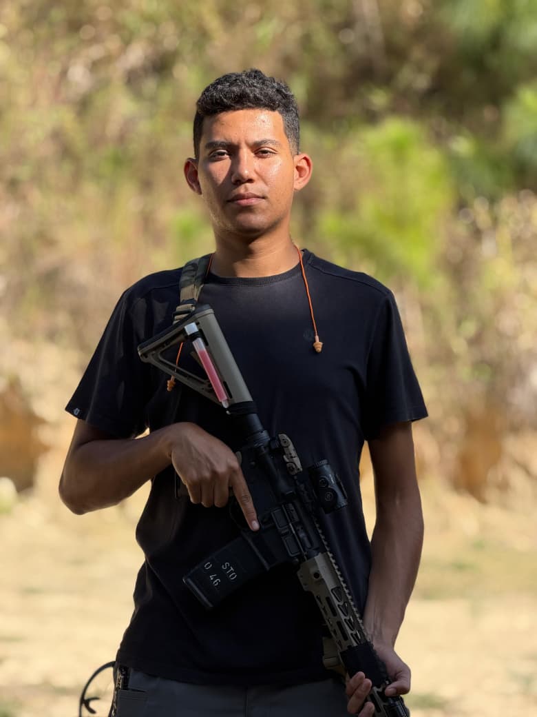 João Vitor Godoy, instrutor de armamento e tiro, segurando um fuzil